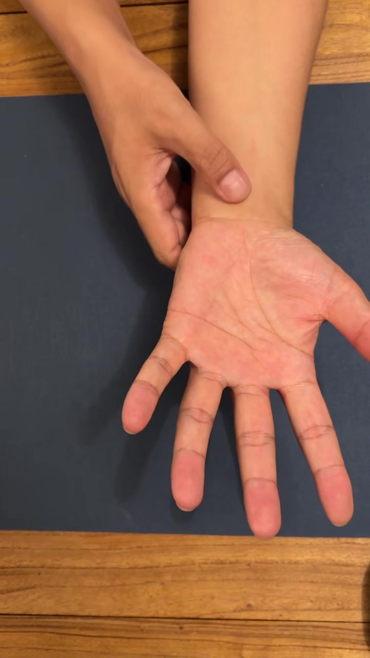 Finger pressing Shenmen HT7 on the inner wrist, just below the little finger